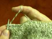 The position of the thumb hidden by rows of knitting