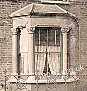 Typical bay window of the front parlour in an early 1900s house. Note the sash windows, the wooden venetian blinds and the lace curtains.