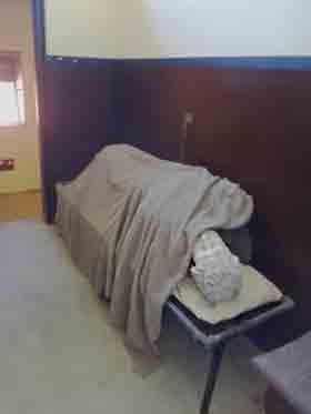 Inside a cell of a casual ward, also known as a dosshouse, showing the narrow bed and the individual work area leading off.